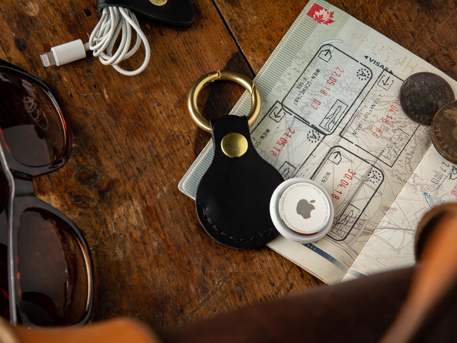 Black handmade leather air tag keyring sitting on a passport