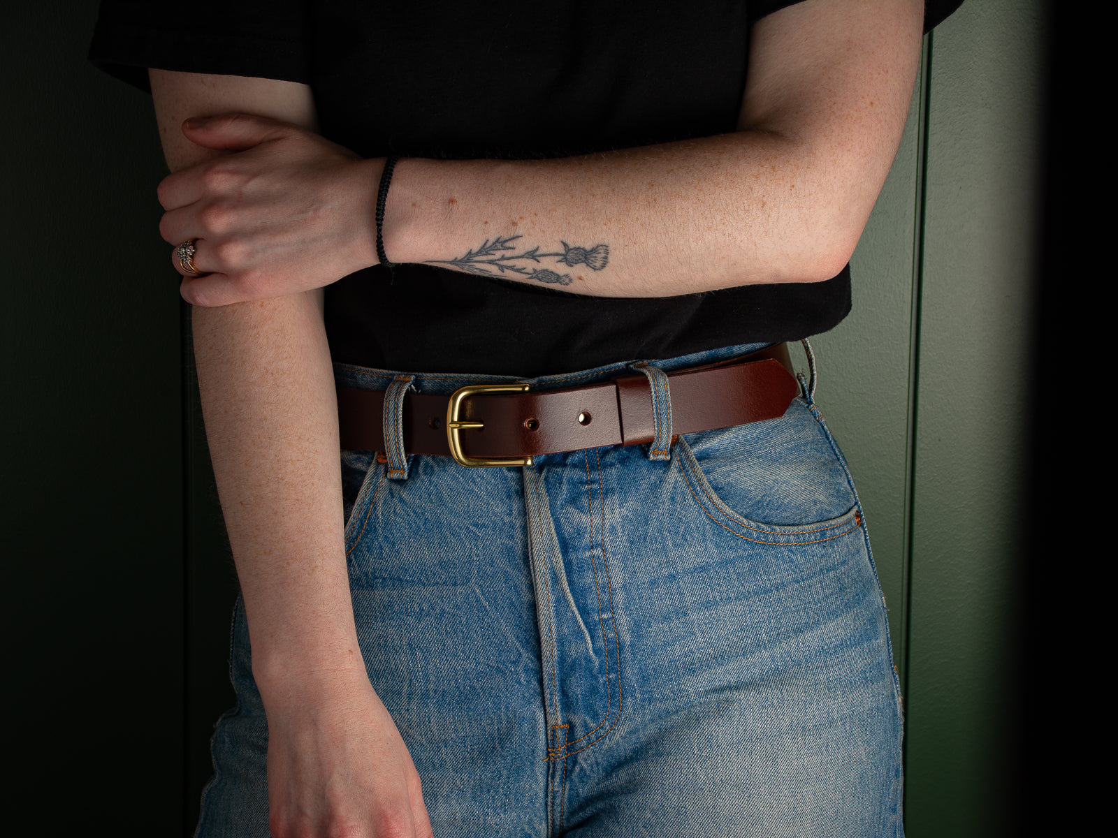 Brown leather Ashfield belt with brass hardware on a woman wearing blue jeans.