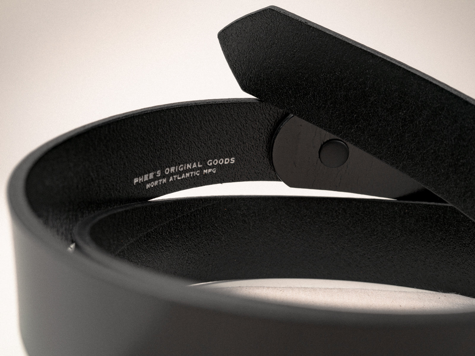 A close-up the logo embosssing on the inside of a black Ashfield leather belt