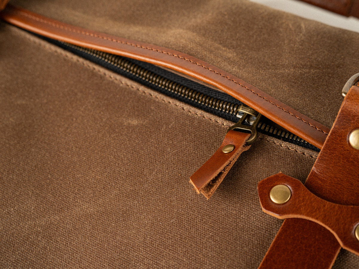 detail photo showing the hidden side zippered pocket on the campbellton canvas messenger bag