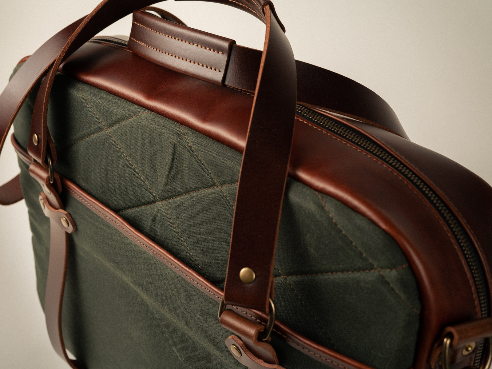detail shot of quilted pattern on side of olive cambpellton messenger bag, and stitched handle detail