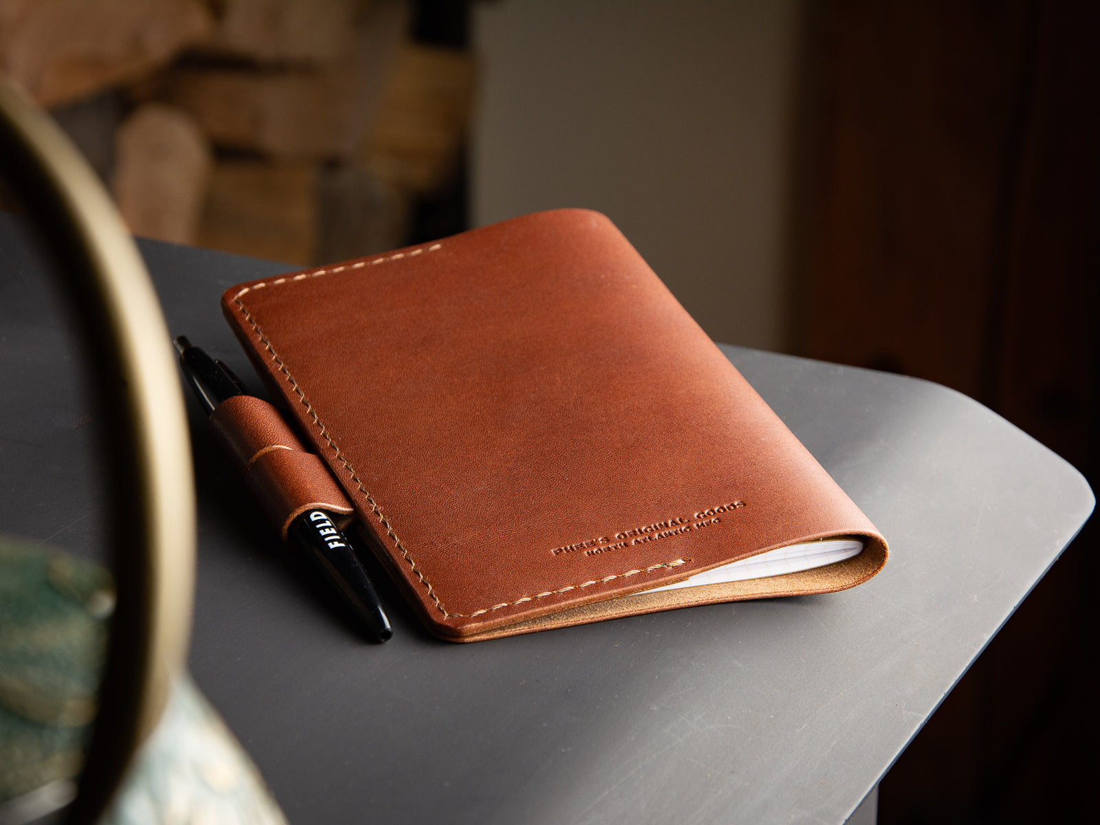 Back side of brown full-grain leather Notebook Sleeve with pen closure