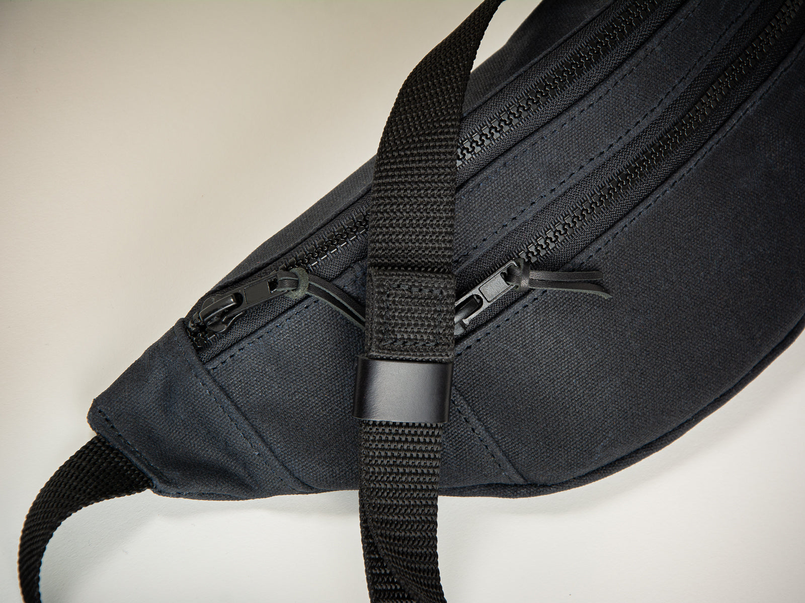 closeup of leather tab on canvas fanny pack with webbing waist or shoulder strap