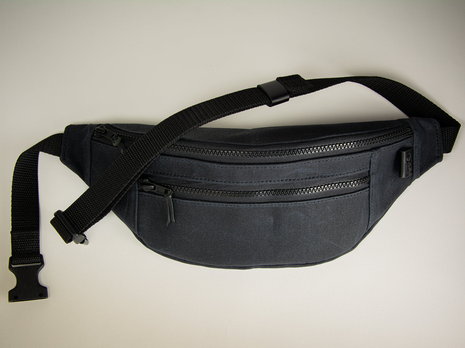 Black canvas fanny pack with leather accents for use over shoulder or around waist clip undone
