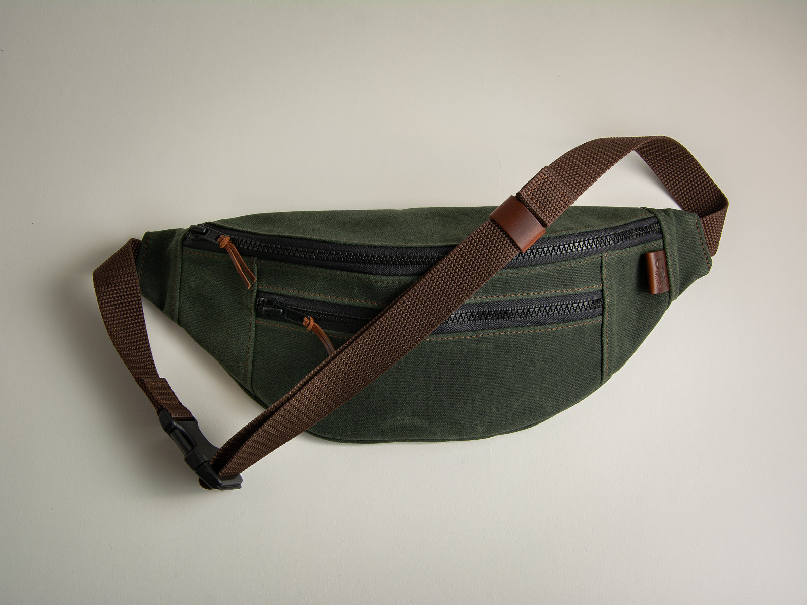 Olive green canvas fanny pack with leather accents for use over shoulder or around waist
