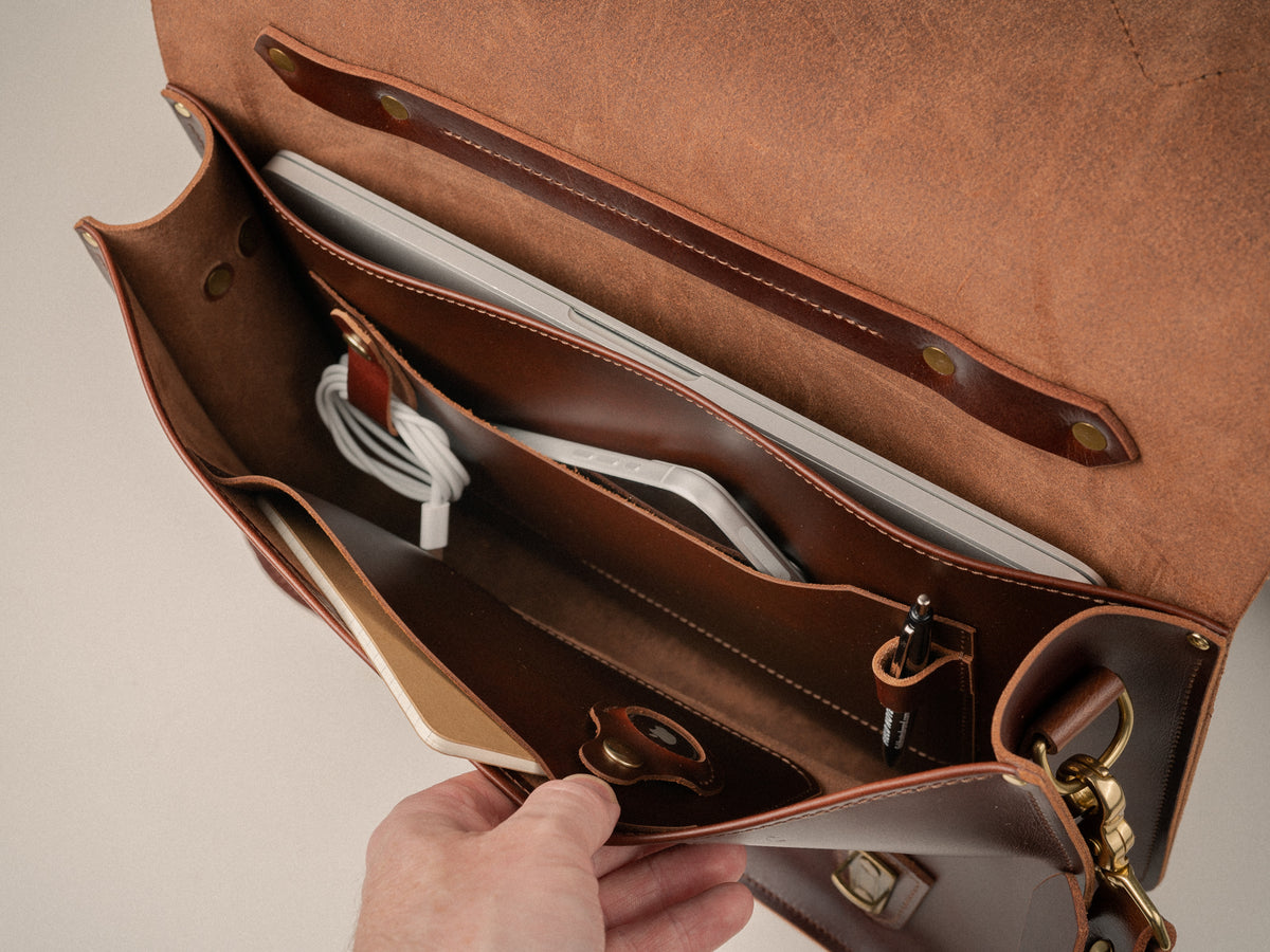 Interior photo of the Glengarry Messenger bag showing the 14" laptop sleeve, pen loop, cord keep, apple air tag pocket and dual notebook pockets big enough for a phone.