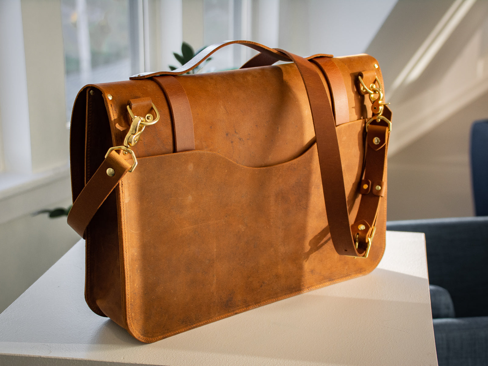 Glengarry messenger bag in wheat. Showing the back of the bag and the shoulder strap in an office.