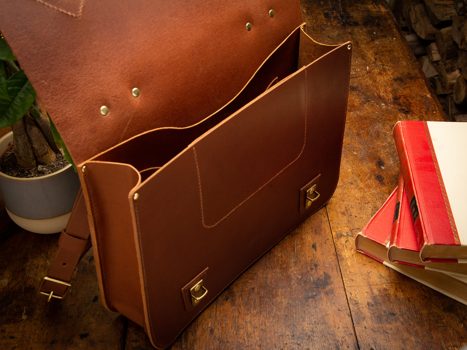 Glengarry messenger bag in tan leather with top open, showing inside pockets and brass hardware