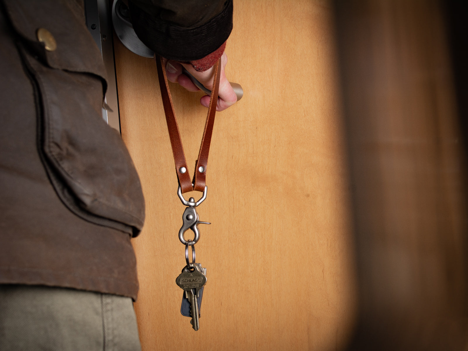Key Lanyard in Tan and Nickel hardware show in use with someone opening a door.