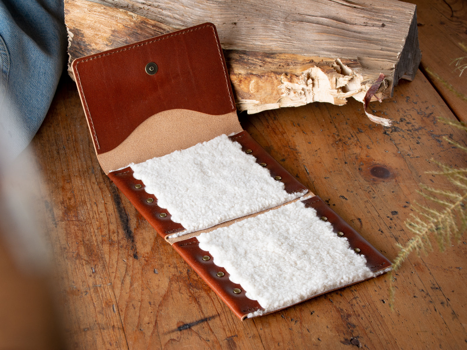 A brown fly fishing wallet sitting on a wooden table.