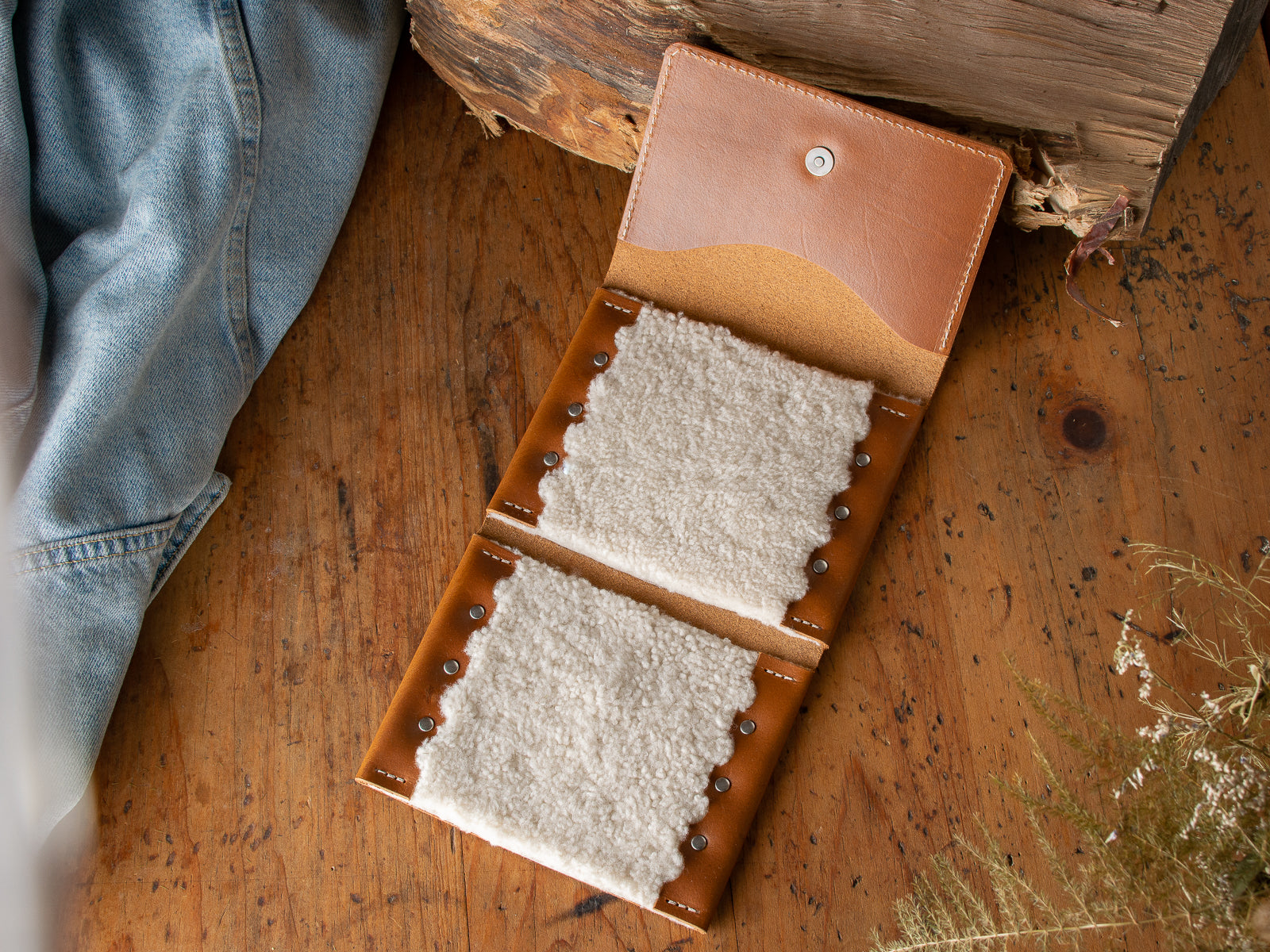 A tan fly fishing wallet sitting on a wooden table.