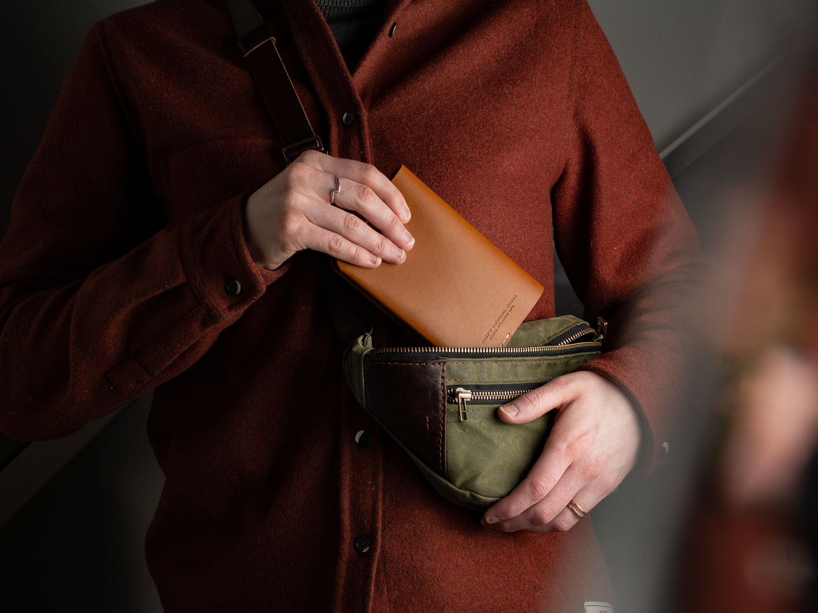 Slipping a tan full-grain leather passport sleeve into a bag