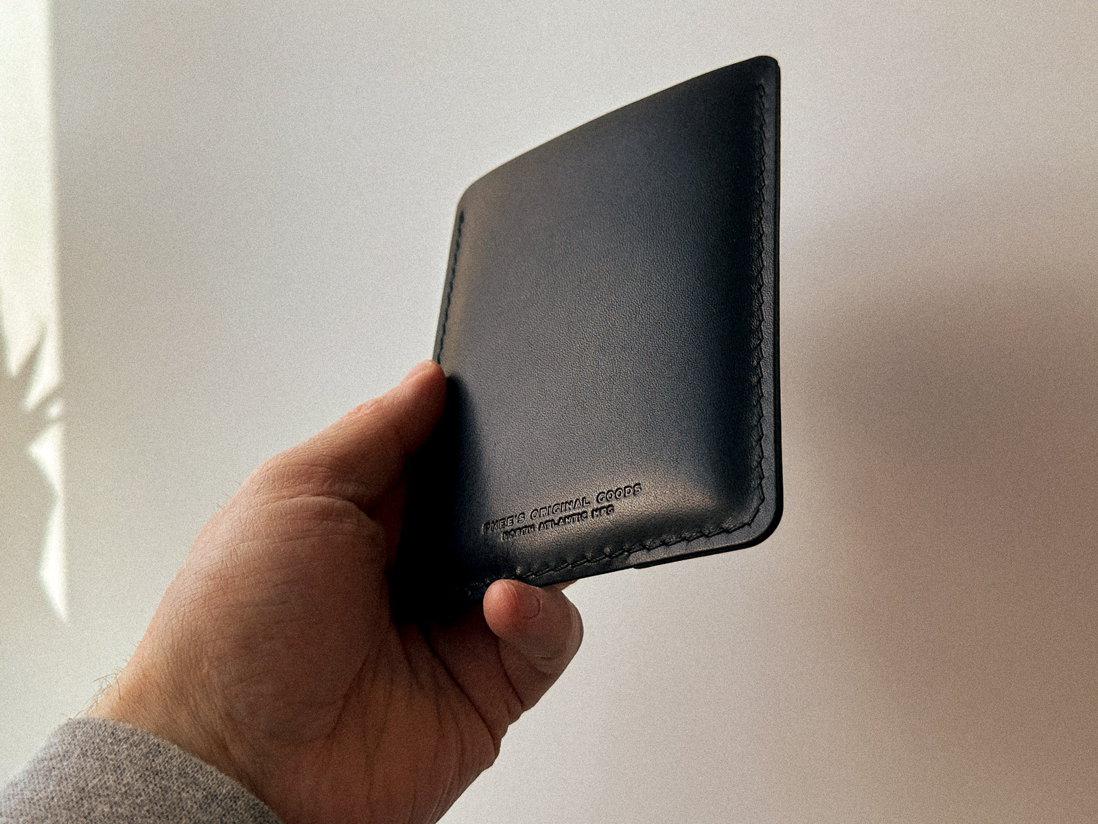 back side of black leather passport slip showing embossed logo
