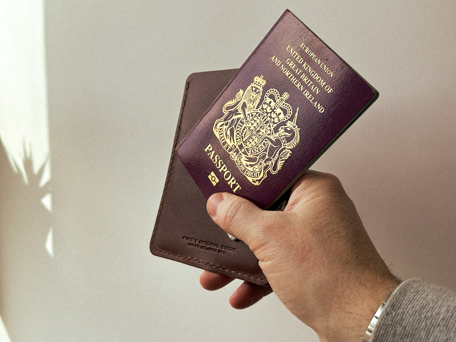 Hand holding a brown leather passport slip and passport
