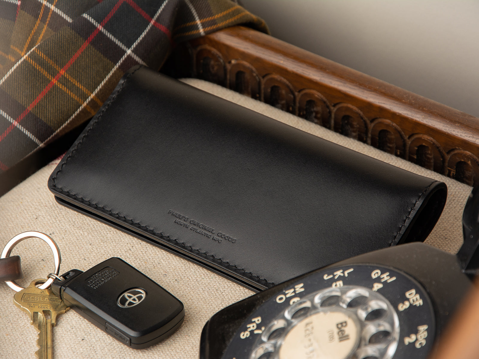 Rosedale black full grain clutch wallet sitting at front entrance table beside toyota car keys.