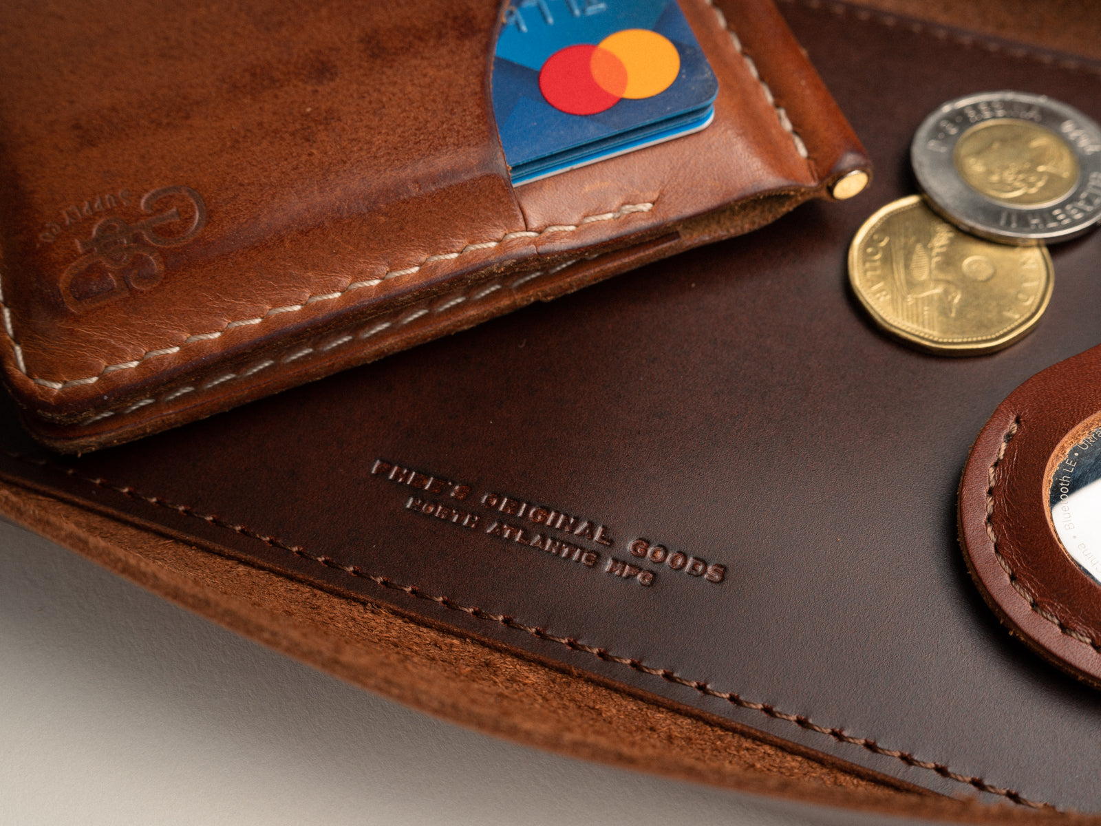 Close up of stitched reinforced bottom of brown leather Valet tray, with wallet, money and airtag