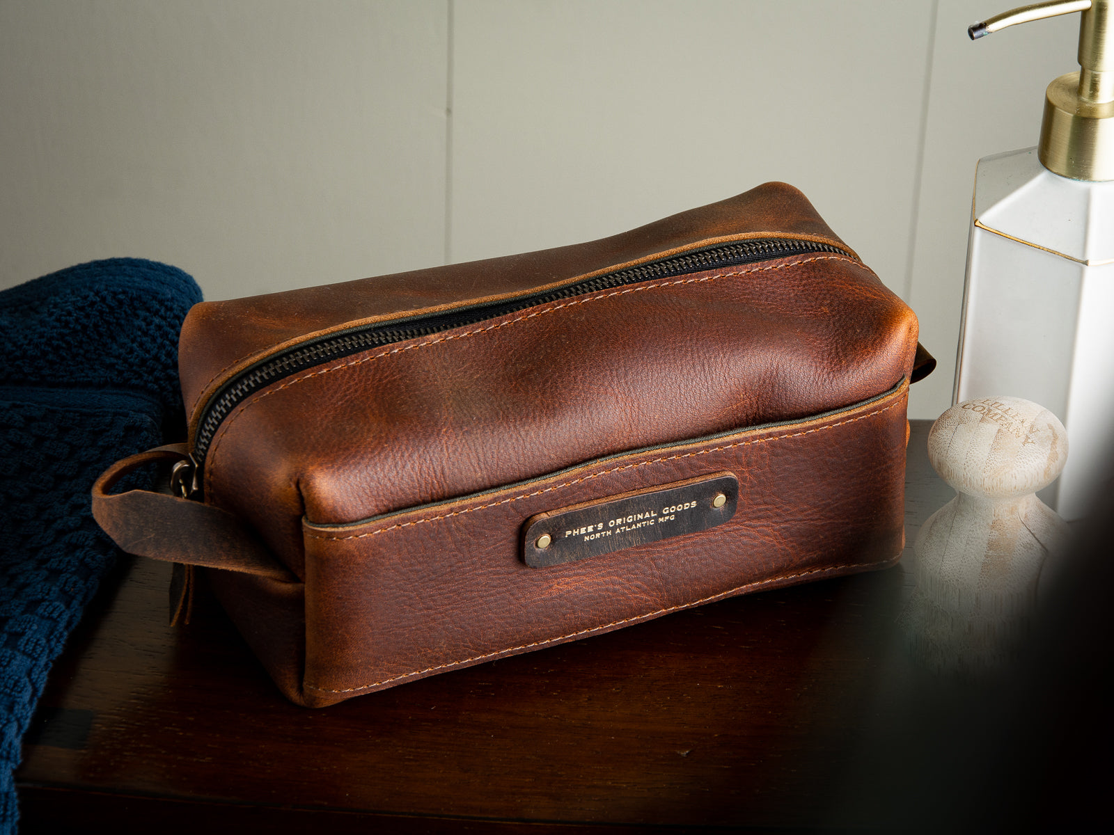 handmade oil tan brown leather dopp kit sitting in a bathroom