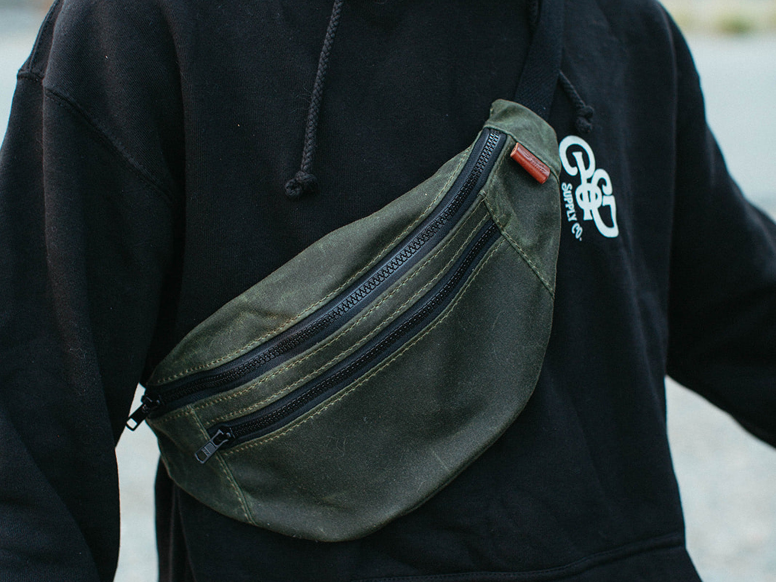 Olive green waxed canvas franey pack over someones shoulder