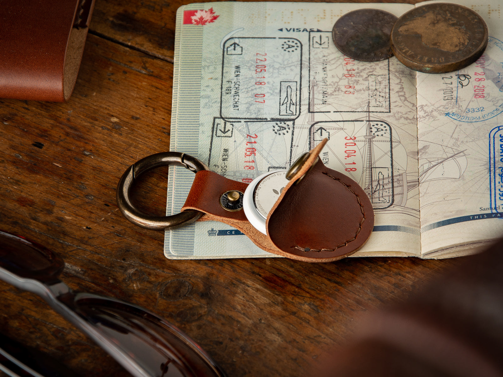 brown leather apple air tag case sits on top of a passport