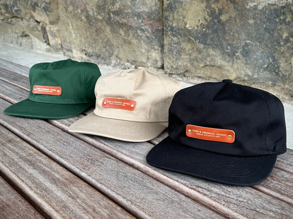 Collection of North Atlantic Hats on a wooden bench with their chestnut leather patches with gold foil embossing