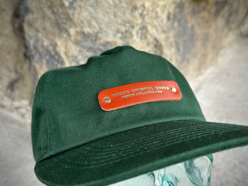 Close up of the North Atlantic Hat in Pine showing the gold foil emboss on the chestnut leather patch