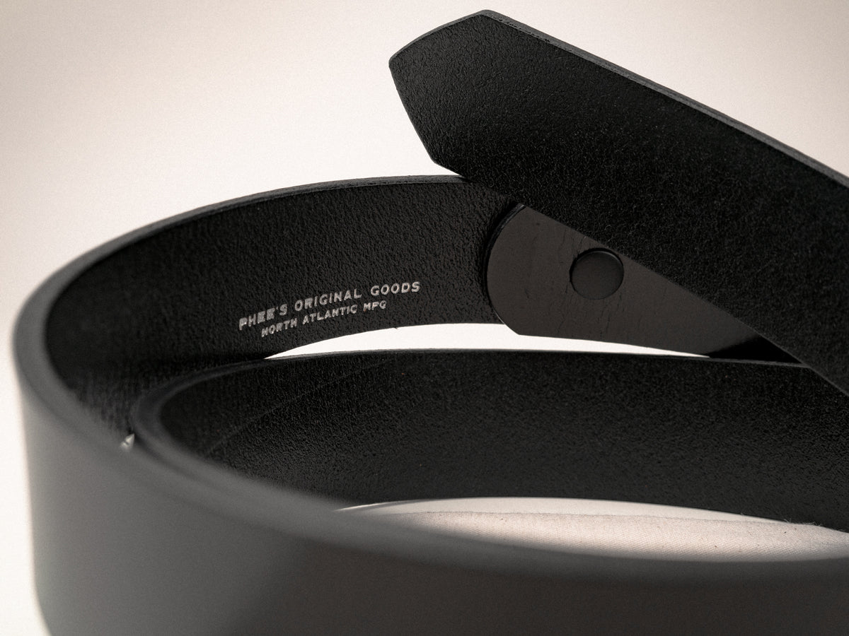 A close-up the logo embosssing on the inside of a black Ashfield leather belt