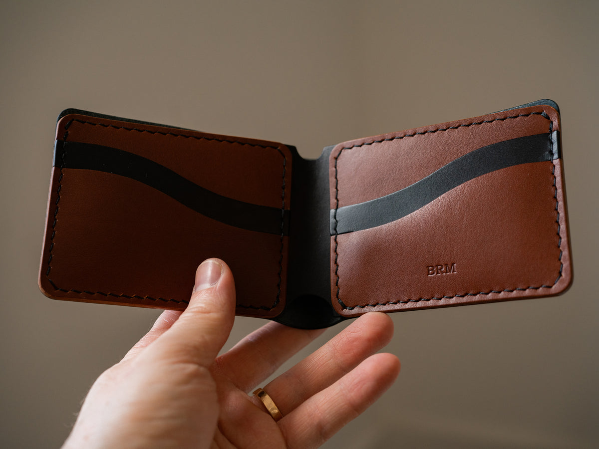 Classic bucklaw bifold wallet in custom colourway of brown and black leather with black stitching and embossed monogram