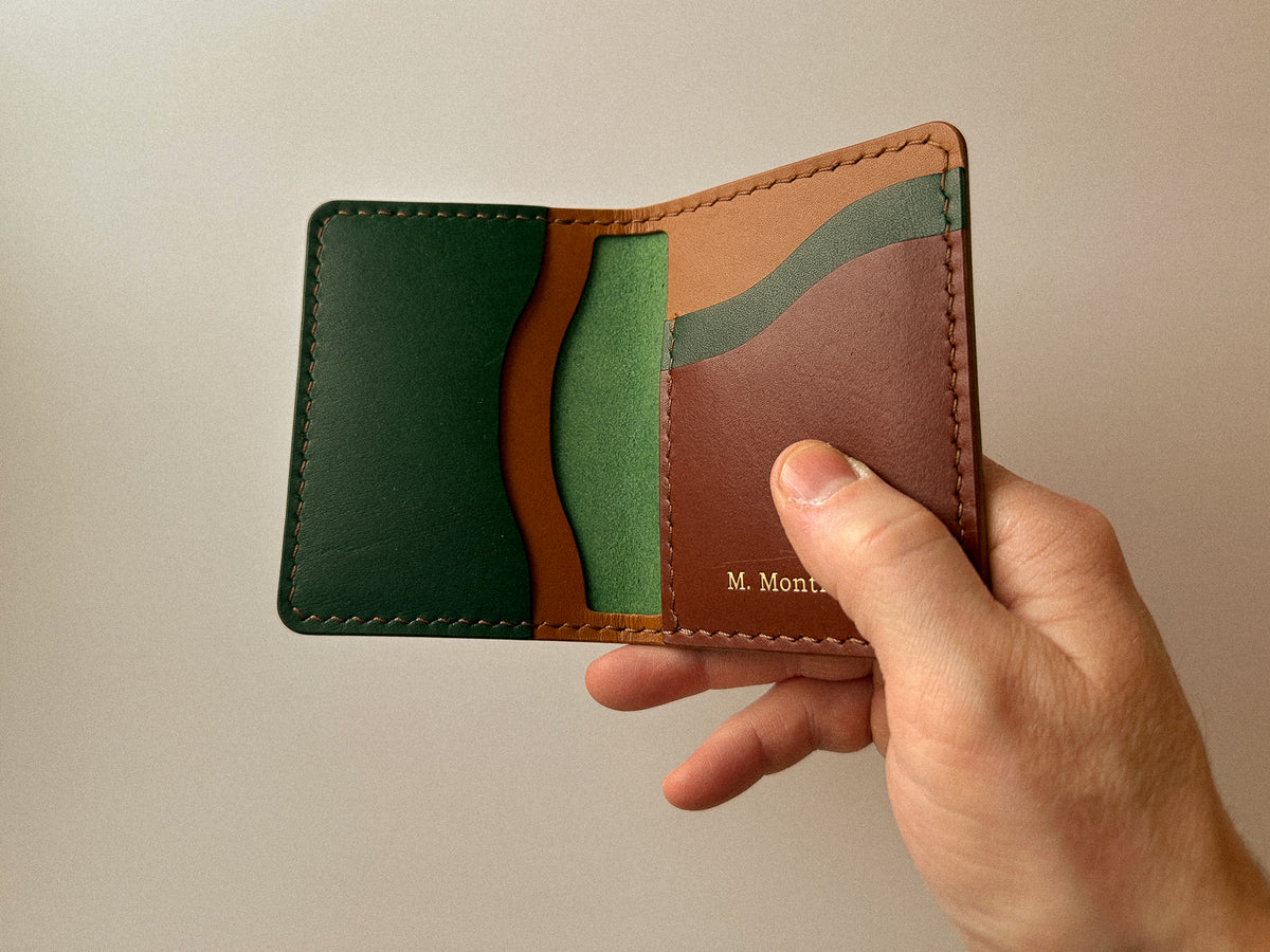 Hand holding a handmade build your own custom Barra leather wallet in pine green, tan and brown