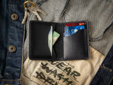 Minimalist bifold Barra wallet in black laying open, showing card and cash slots