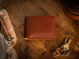 Bucklaw bifold wallet in brown - laying on rustic table 