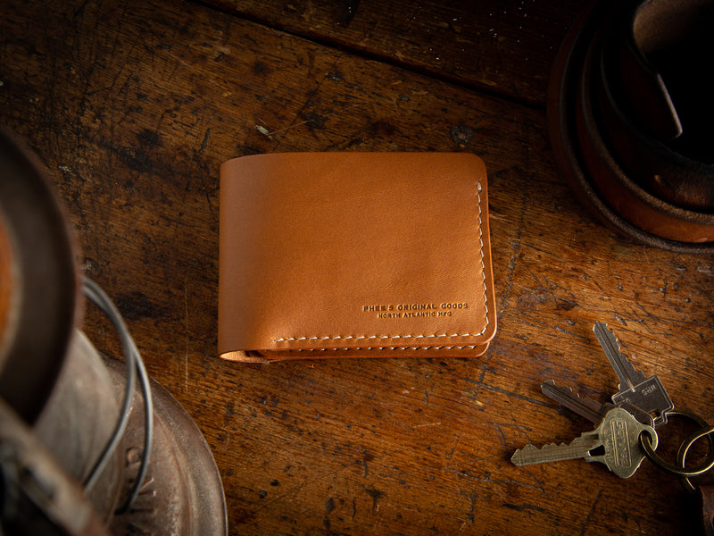 Bucklaw bifold wallet in tan - laying on rustic table 