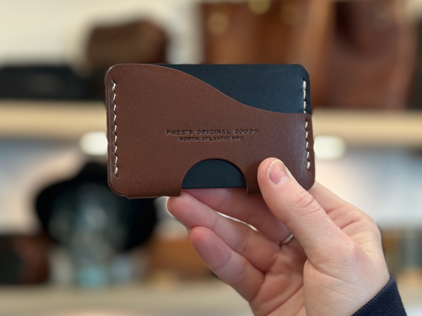 Hand holding a navy and brown build your own custom Aberdeen leather wallet