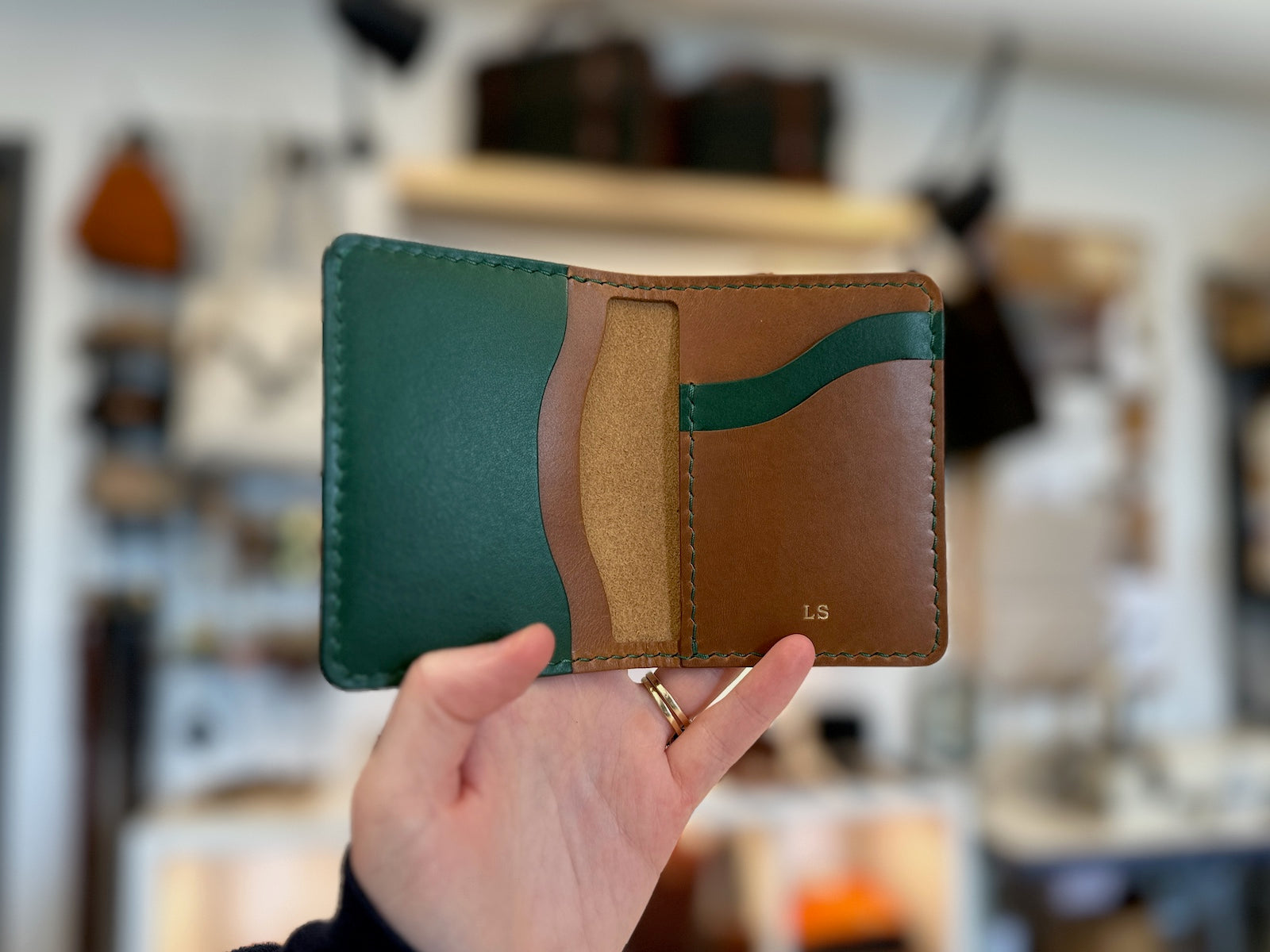 Hand holding a handmade build your own custom Barra leather wallet in pine green and tan