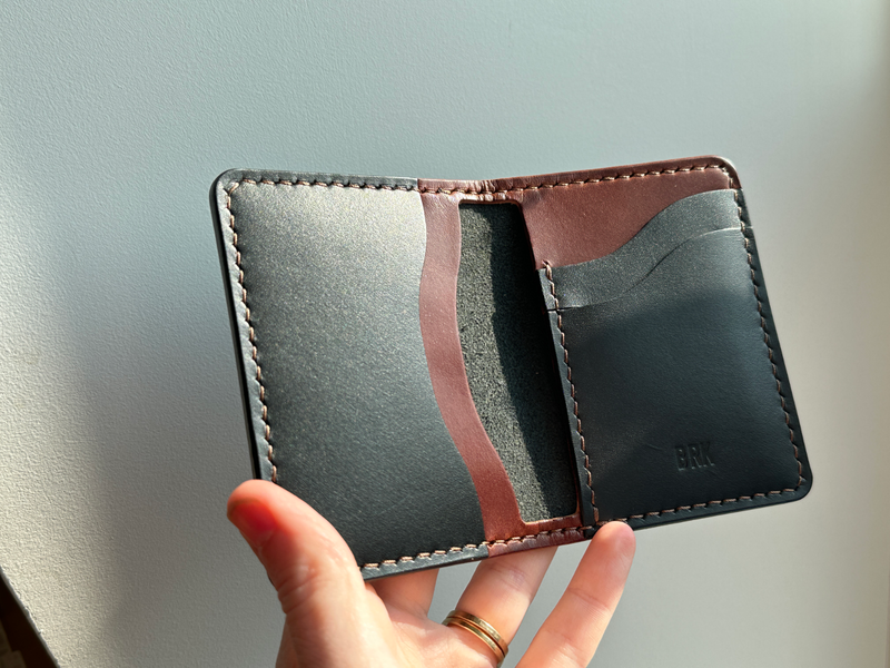 Hand holding a custom build your own barra leather wallet with brown and black pockets and monogram
