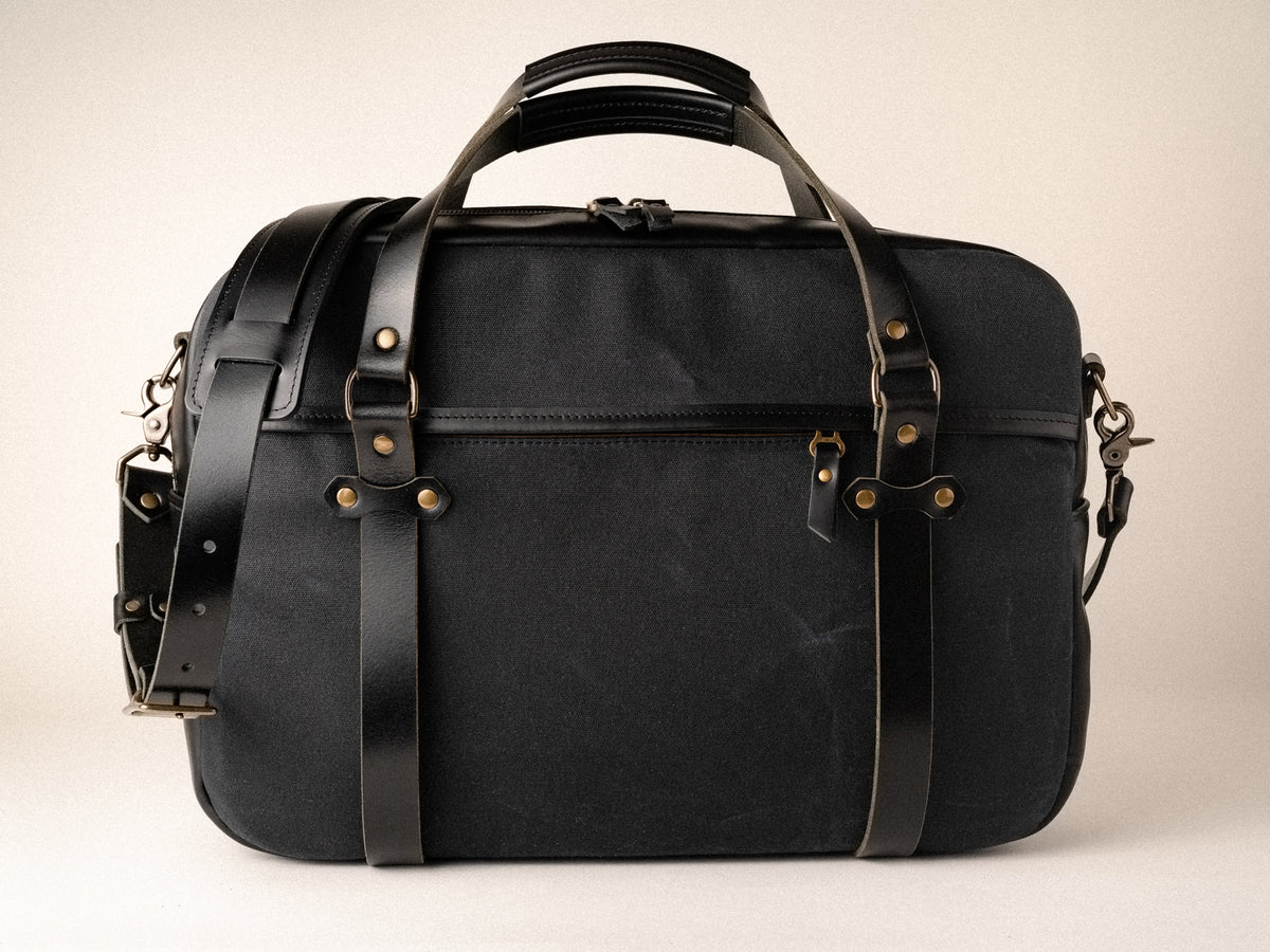 side view of campbellton laptop bag in black canvas and leather, showing the zippered size pocket hidden by placket