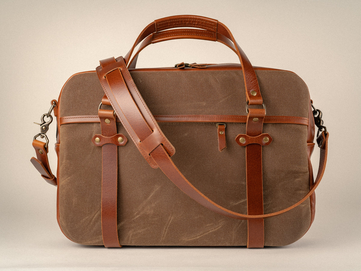 campbellton messenger bag with hidden pocket poking under placket of nutmeg canvas, draped in padded cross-body strap
