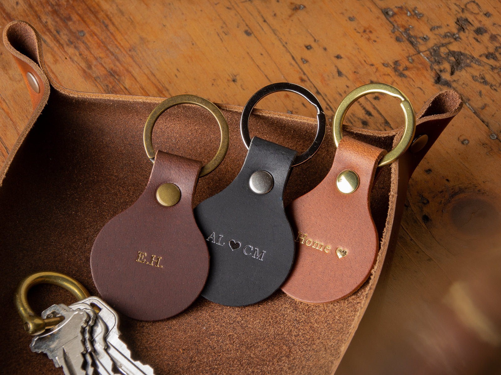 three custom leather keychains sitting in a valet tray