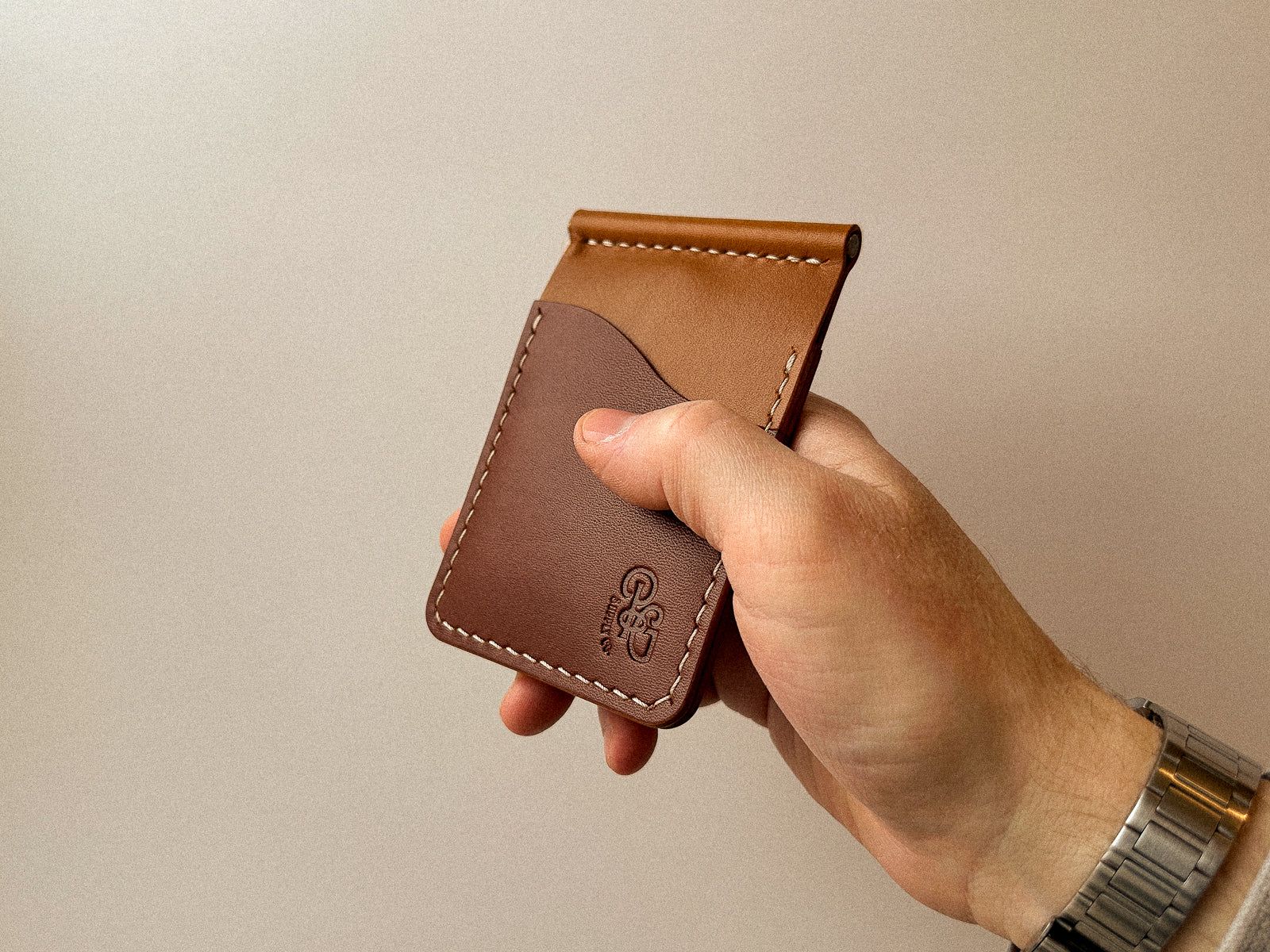 hand holding a custom leather build your own duvegan wallet with tan and brown leather