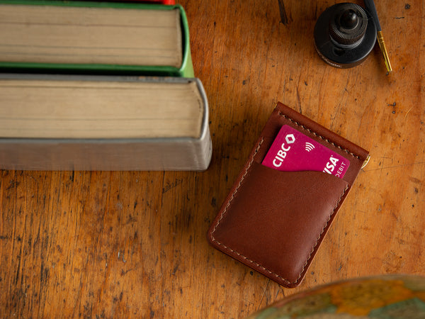 Donvegan money clip card wallet in brown laying on table beside books