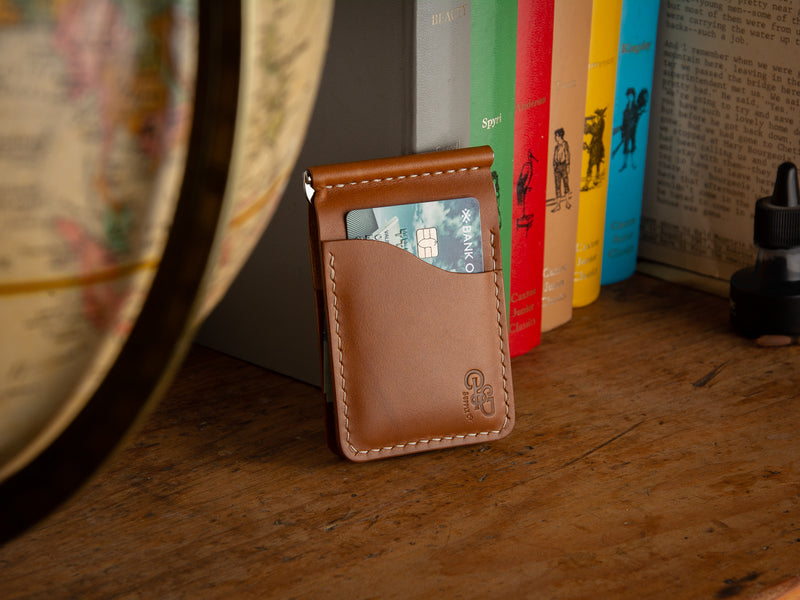 Dunvegan money clip card wallet in tan sitting on a shelf of books