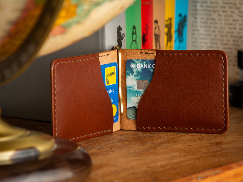 Dunvegan money clip card wallet in brown sitting on a shelf of books