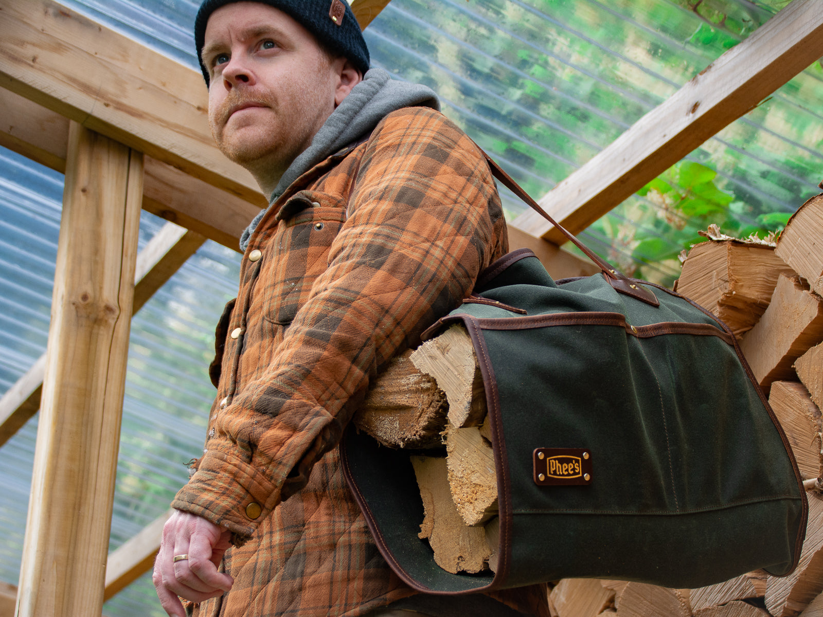 Kyle with an olive Glen Morrison log carrier slung over his shoulder, full of wood to keep the stove burning. 