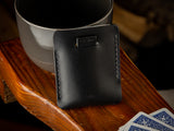 Kenloch pull tab minimalist card wallet sitting on an arm chair in black full grain leather