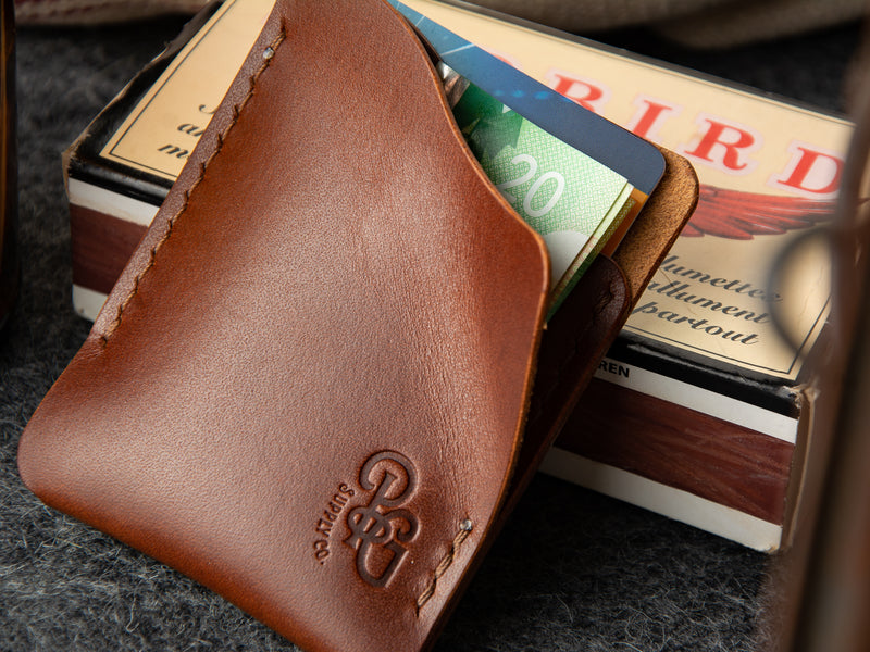 Brown kenloch minimalist card wallet with pulltab, showing from flap pocket open with cards and cash