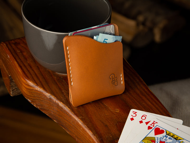 Kenloch pull tab minimalist card wallet sitting on an arm chair in tan full grain leather