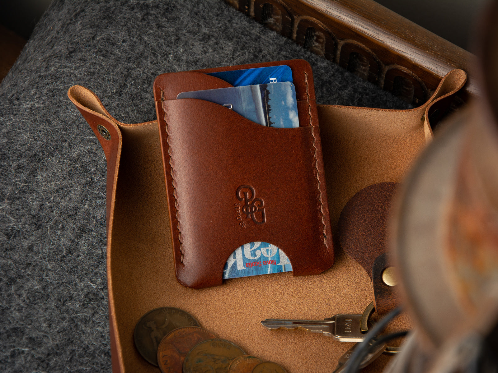 Brown lewis money clip card wallet shown in a leather valet tray catch all.