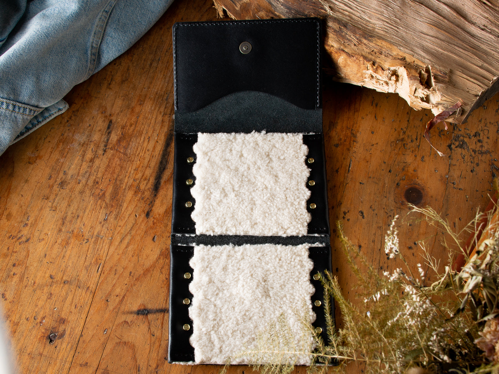 A black fly fishing wallet sitting on a wooden table.