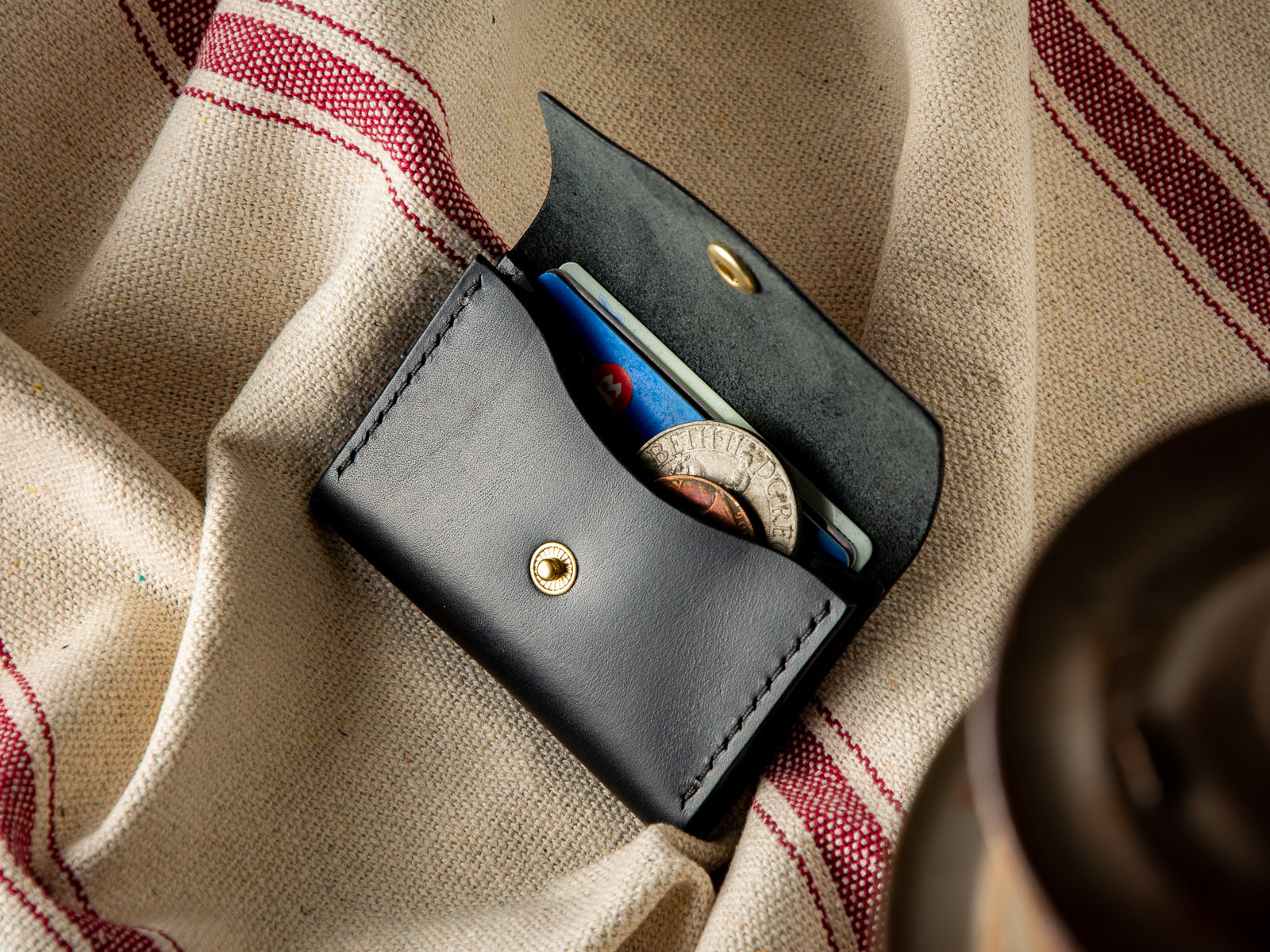 black no. 11 full-grain leather pouch wallet, open showing coin, cash and card pocket.
