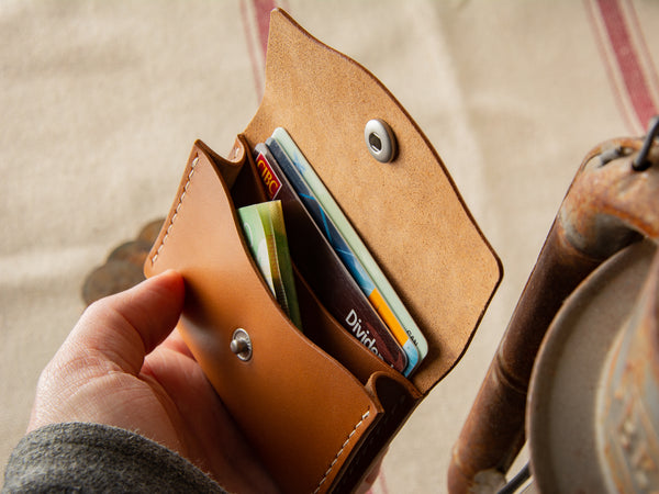 full-grain leather tan no. 11 pouch wallet, open in someones hand showing card and cash pockets