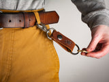 Tan leather with nickel hardware hooked into pant belt loop